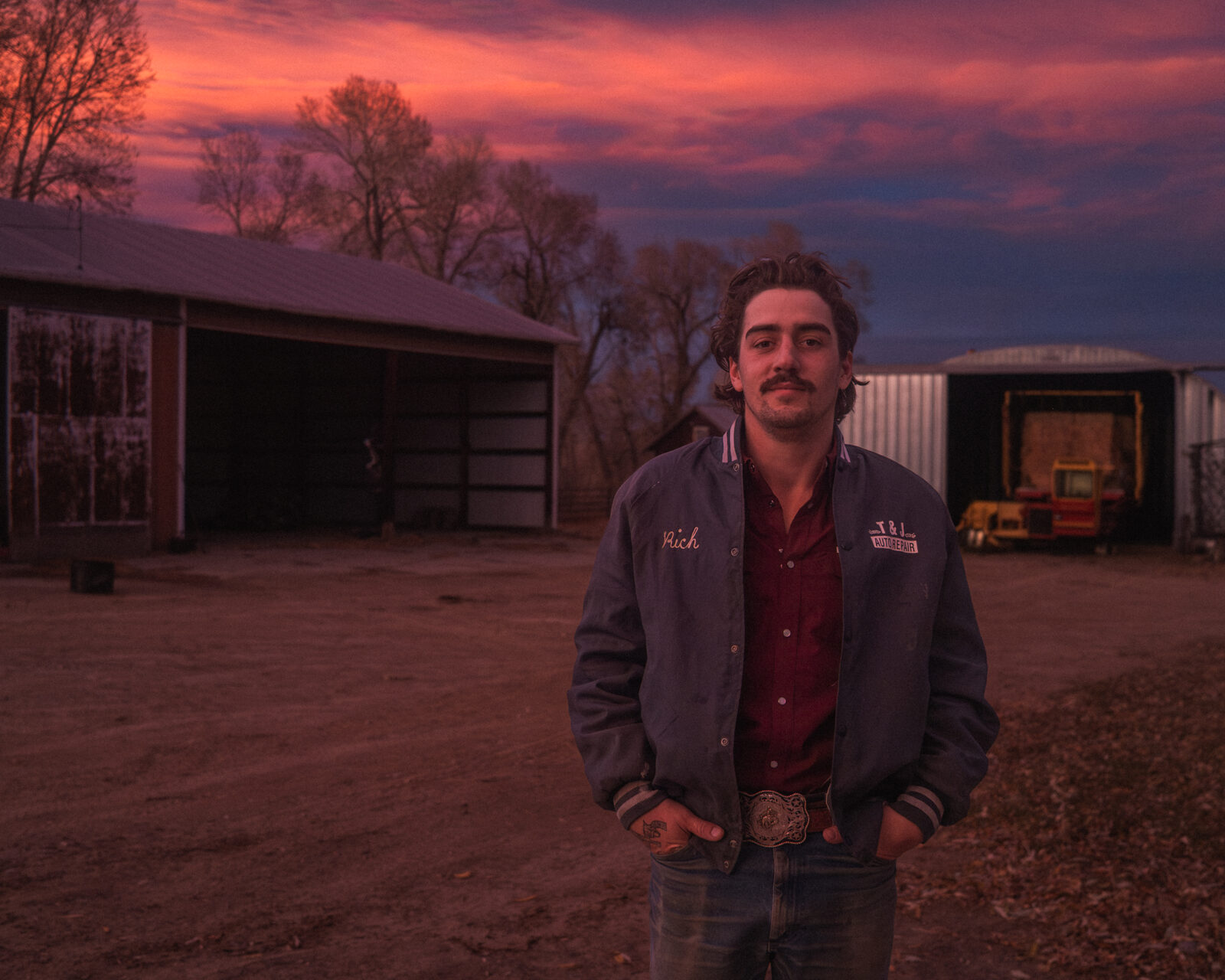 A young man at dusk under a pink sky